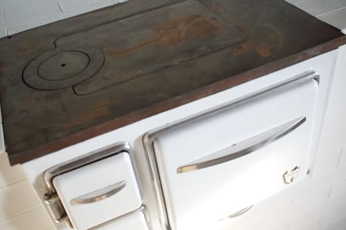 Rustic wood cooktop with white oven doors at Finques Garcia Enrich, Palafrugell
