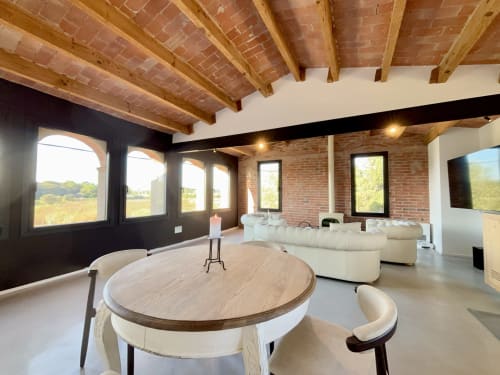 Modern loft-style lounge at Finques Garcia Enrich in Palafrugell with exposed brick, wooden beams, round table, and