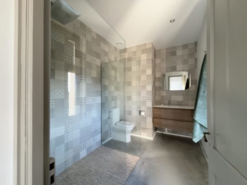 Modern bathroom with walk-in shower, wood vanity, and patterned tile walls at Finques Garcia Enrich hotel in Palafrugell