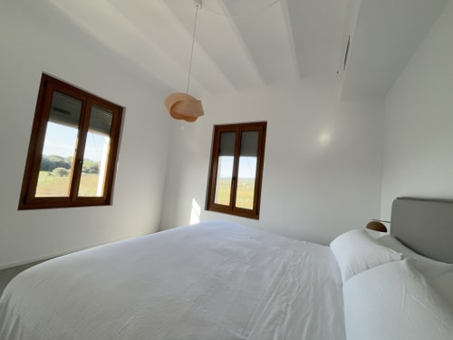 Bright bedroom at Finques Garcia Enrich in Palafrugell with white walls, wooden windows overlooking countryside, and modern