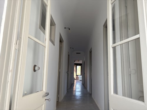 Long hallway with white doors and windows at Finques Garcia Enrich hotel in Palafrugell, Spain