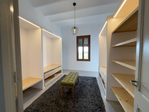 Modern walk-in closet with built-in shelving, bench seating, and pendant lighting at Finques Garcia Enrich hotel in