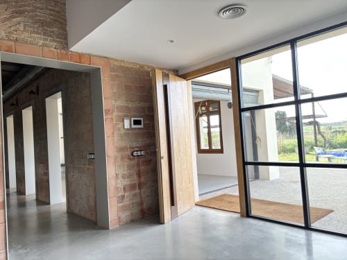 Modern entryway at Finques Garcia Enrich in Palafrugell with exposed brick, concrete floors, glass doors and countryside