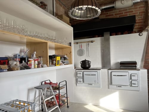 Modern communal kitchen at Finques Garcia Enrich in Palafrugell with white cabinetry, dual ovens, and open shelving with