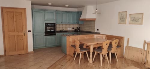 Udai Apartment kitchen and dining area at Residence Rodolon in Mazzin with turquoise cabinets and wooden furniture