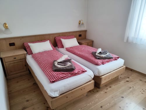 Twin beds with red checkered bedding in Udai Apartment at Residence Rodolon, Mazzin, mountain view room with wooden