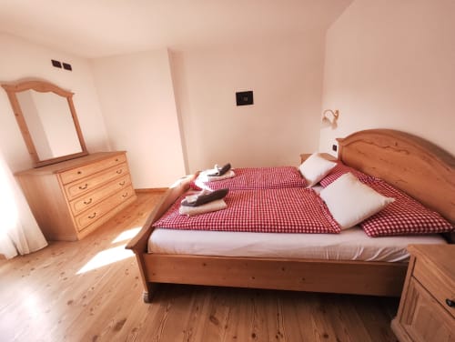 Bright bedroom in Udai Apartment at Residence Rodolon, Mazzin, featuring wooden furniture, twin beds with red checkered