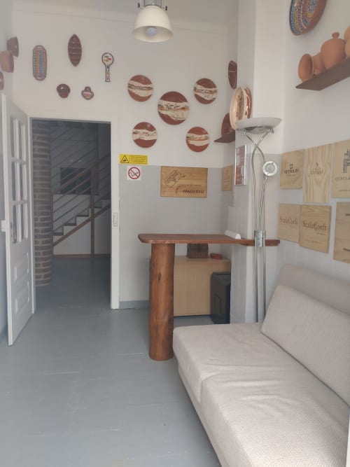 Área de estar aconchegante em Casa do Pão com mesa de madeira, assentos bege, paredes brancas decoradas com cerâmica rústica