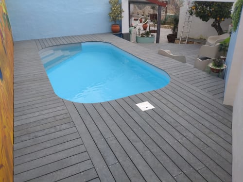 Bright blue rectangular pool surrounded by gray composite decking at Casa do Pão apartment in Campinho, Portugal with lounge