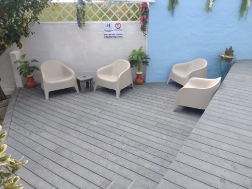 Modern pool area seating at Casa do Pão with white curved chairs, potted plants, and blue walls in Campinho