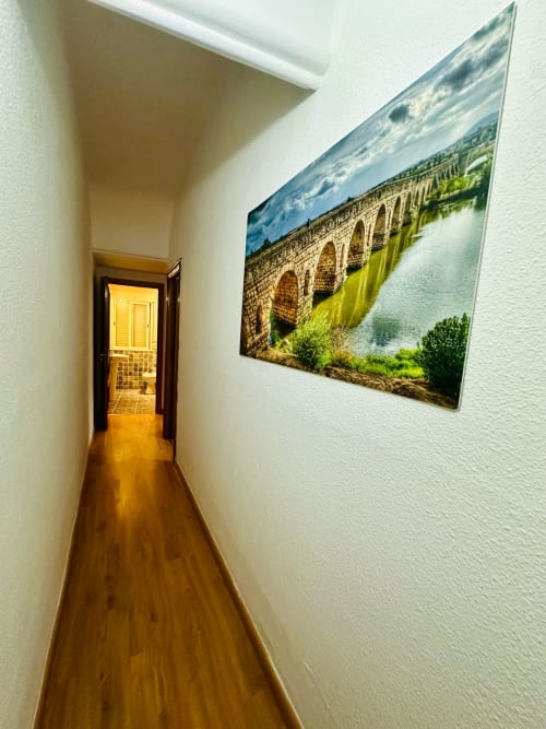 Pasillo estrecho en apartamento de Mérida con piso de madera e impresión de acueducto histórico en pared blanca