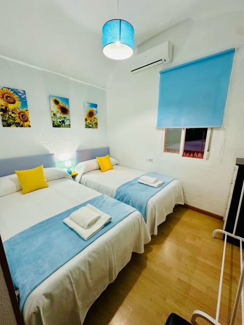 Luminosa habitación doble en apartamento Gestyp-AT de Mérida con acentos azules, arte de girasoles y pisos de madera