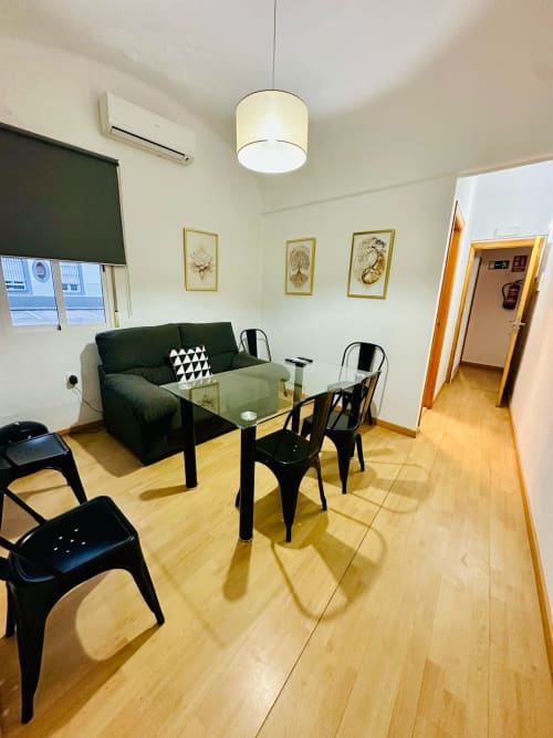 Moderna sala de estar en Mérida con sofá verde, mesa de comedor negra y vistas a la ciudad