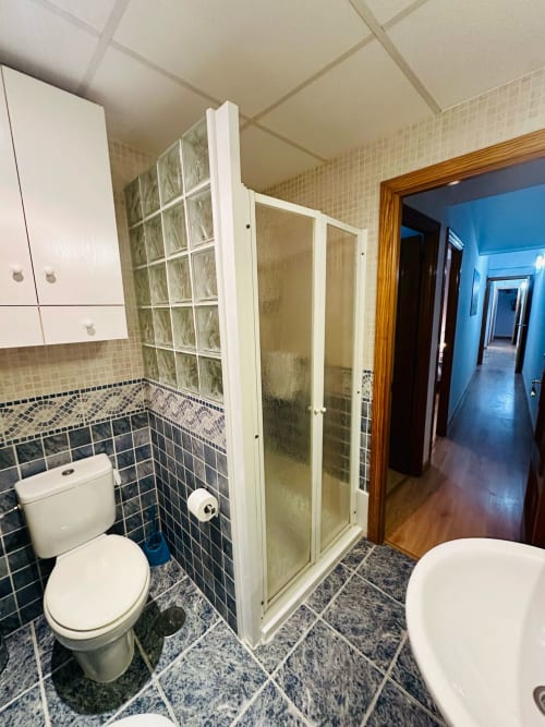 Baño con ducha, inodoro y lavamanos en apartamento Gestyp-AT en Mérida con paredes alicatadas y accesorios modernos