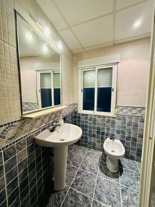 Baño moderno en apartamento Gestyp-AT, Mérida con doble lavabo, paredes alicatadas y vistas a la ciudad