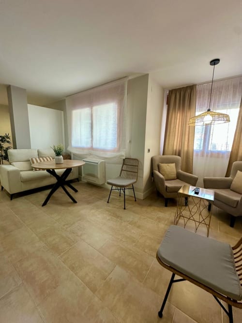 Sala de estar moderna en Mérida con mobiliario beige, vistas de la ciudad y decoración contemporánea