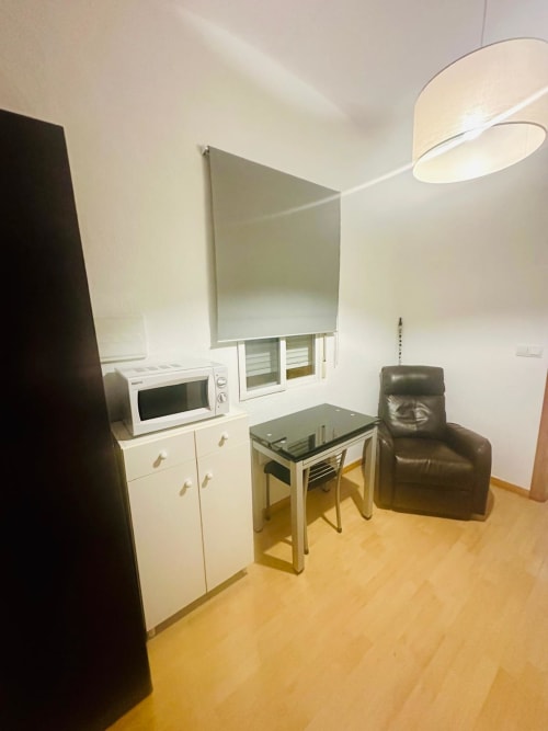 Estudio moderno en Mérida con cocineta, mesa de comedor, sillón de cuero e iluminación contemporánea