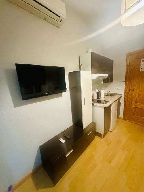 Moderno kitchenette de apartamento con televisor montado en pared en el hotel Gestyp-AT de Mérida, España