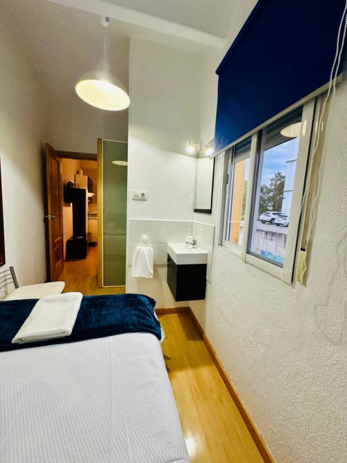 Recámara moderna en Mérida con baño en suite, vistas a la ciudad y mobiliario contemporáneo