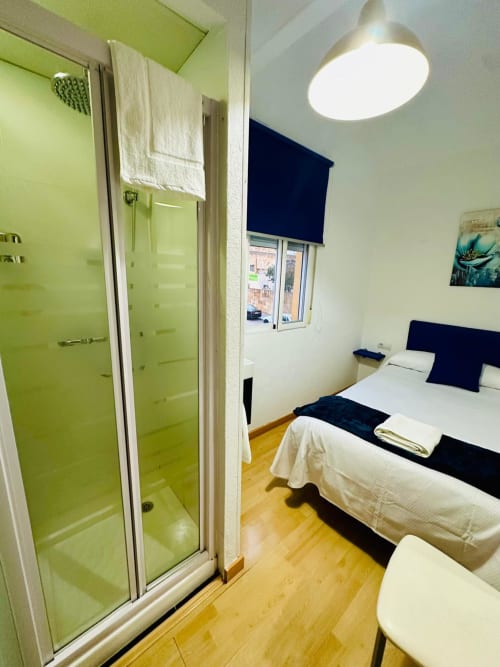 Moderna recámara con cabina de ducha verde lima, acentos negros, piso de madera y vista de la ciudad en Mérida