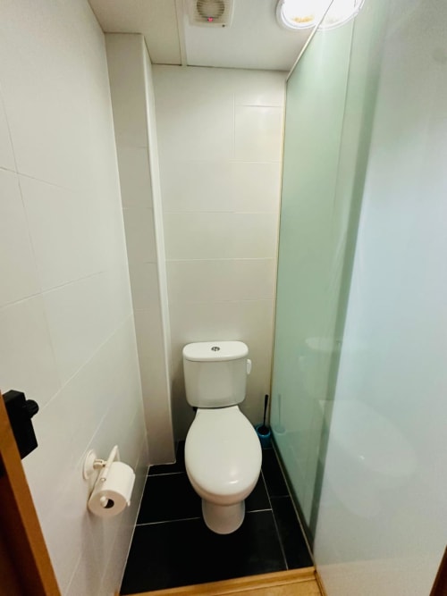 Baño compacto en apartamento Gestyp-AT, Mérida con inodoro blanco, paredes azulejeadas y piso negro