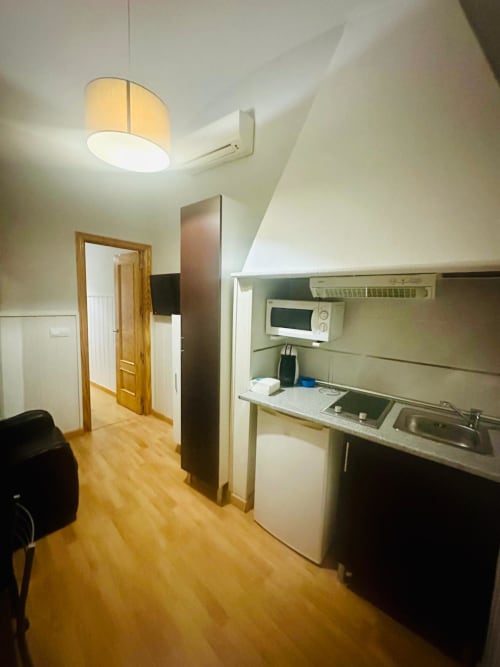 Moderna cocina de apartamento con techo abuhardillado, piso de madera y kitchenette compacta en Mérida