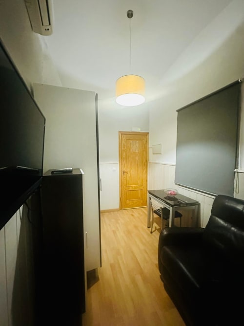 Sala de estar moderna en Mérida con pizarras, asientos de cuero, piso de madera e iluminación colgante