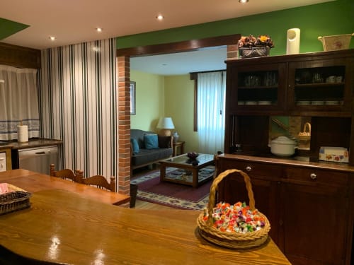Comedor de Casa La Huerta con mesa de madera, paredes verdes, mueble de madera oscura y salón diáfano en Cangas de Onís