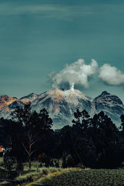 Majestuoso volcán con cumbre nevada elevándose sobre paisaje boscoso cerca de Cangas de Onís