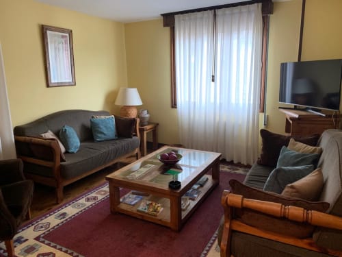 Acogedora sala de estar en la casita Casa La Huerta con sofá, TV, muebles de madera y vistas al jardín en Cangas de Onís