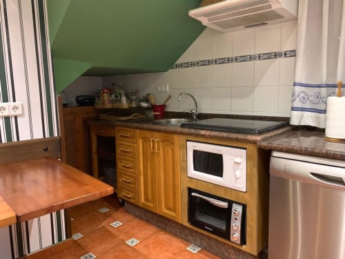 Cocina moderna en la casita Casa La Huerta en Cangas de Onís con muebles de madera, electrodomésticos de acero inoxidable y tonos de terracota