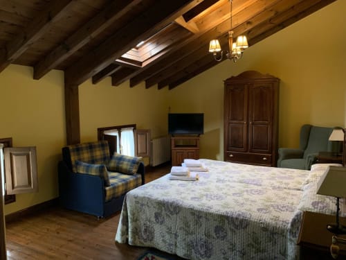 Espacioso dormitorio en Casa La Huerta con vigas vistas, paredes amarillas y vistas al jardín en Cangas de Onís