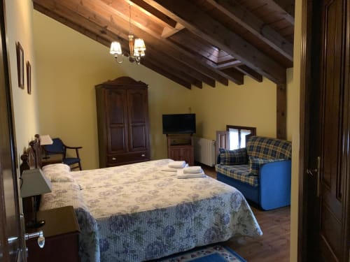 Amplio dormitorio de Casa La Huerta en Cangas de Onís con vigas de madera vista, paredes amarillas y vistas al jardín