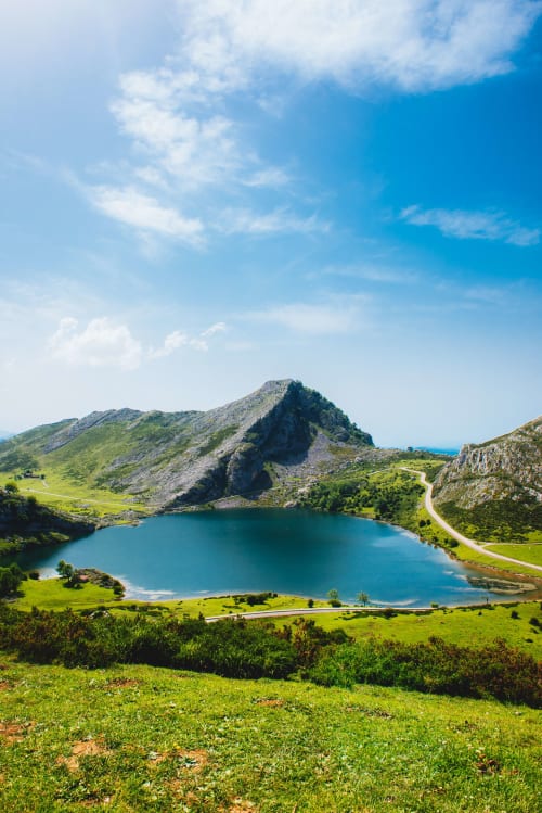 Lago alpino pintoresco rodeado de prados verdes y cimas rocosas cerca de Casa La Huerta, Cangas de Onís