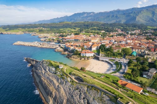 Vista aérea de Cangas de Onís, pueblo costero asturiano con montañas, playa y coloridos edificios