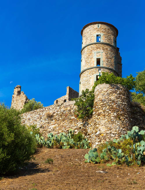 Tour historique en pierre avec toit en terre cuite à Mazet Cavalaire, Cavalaire-sur-Mer, entourée de végétation méditerranéenne