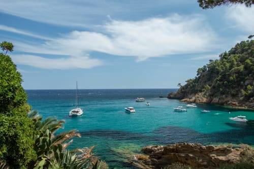 Crique turquoise avec voiliers mouillés au large de Cavalaire-sur-Mer, côte rocheuse et végétation méditerranéenne