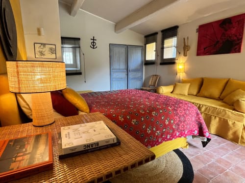 Cozy Saint Martin B&B bedroom in Ollioules with red patterned bedding, yellow sofa, and warm lighting