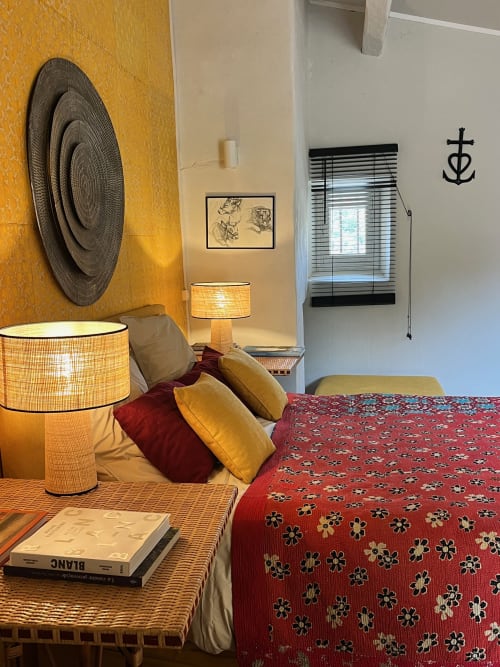 Cozy bedroom at Saint Martin B&B in Ollioules with woven lamp, red patterned bedding, and nautical décor