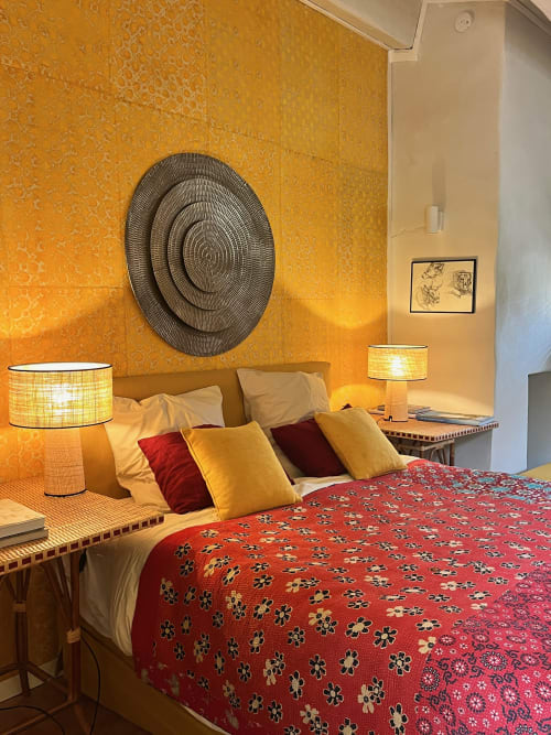 Cozy bedroom at Saint Martin B&B in Ollioules with warm golden walls, red patterned bedspread, and decorative circular wall