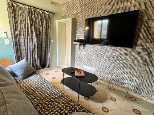 Modern hotel room at Saint Martin BnB in Ollioules with wall-mounted TV, patterned curtains, and contemporary furnishings.