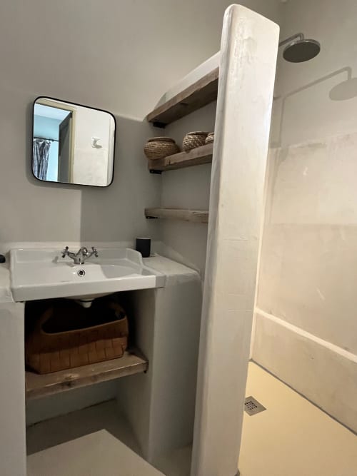 Modern bathroom at Saint Martin B&B in Ollioules with pedestal sink, mirror, shelving, and shower area