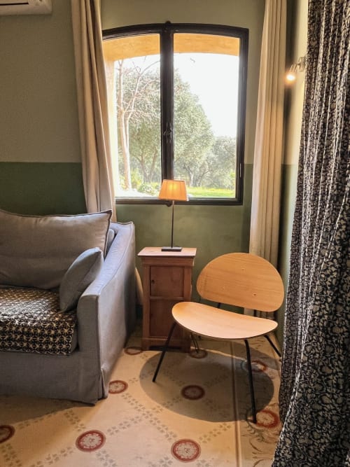 Saint Martin B&B room in Ollioules with seating area, armchair, wooden chairs, and garden view through French doors
