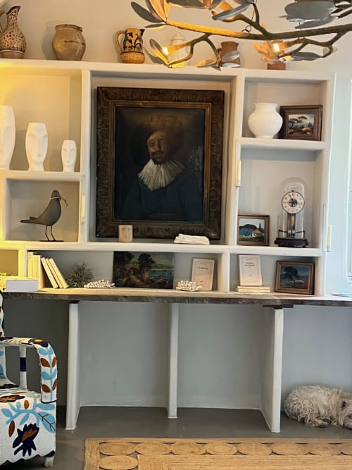 Élégante bibliothèque intégrée au Gîte Saint Martin à Ollioules, France, présentant des œuvres d'art, des vases en céramique blanche et des livres