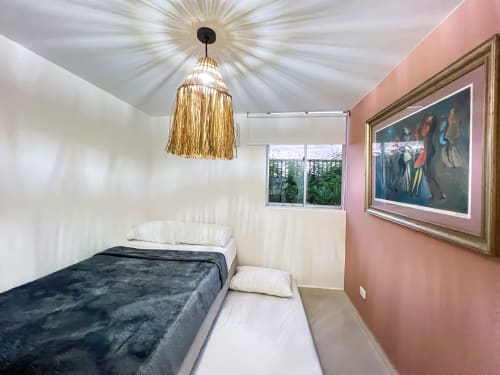 Habitación moderna del hotel Olamar Living en Santiago de Tolú con lámpara colgante dorada, pared de acento rosa y vistas al jardín