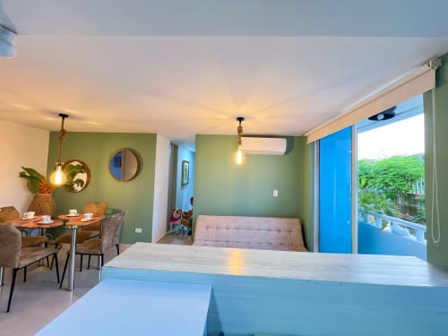Sala de estar moderna con paredes verdes, área de comedor y puerta de balcón azul con vistas al jardín en Olamar Living
