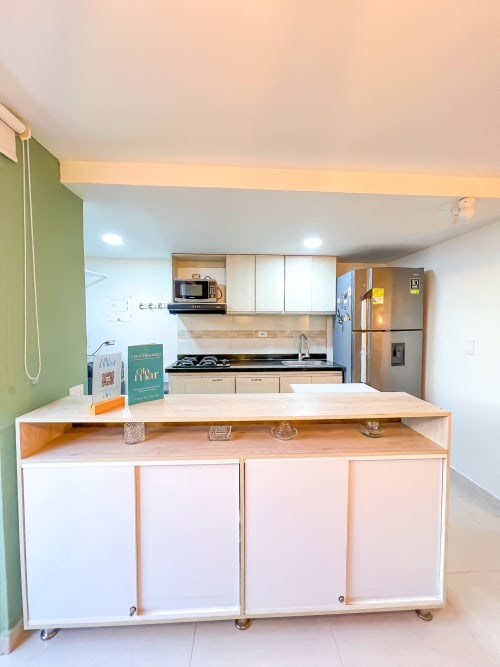 Cocina moderna con isla central blanca, electrodomésticos de acero inoxidable y pared de acento verde en el hotel Olamar Living