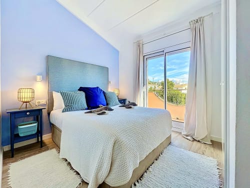 Dormitorio moderno en la casa Mar Blau de Estartit Rental con balcón con vista al mar, cabecero azul y decoración contemporánea