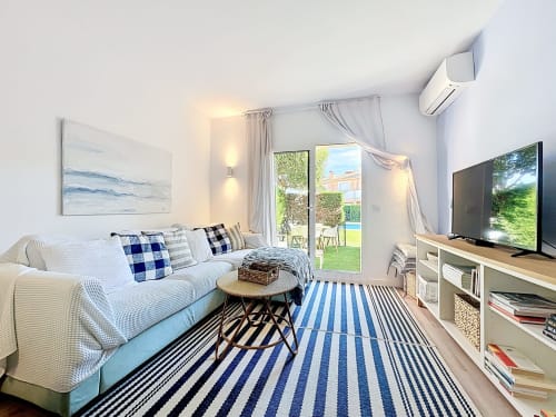 Dormitorio luminoso en Estartit Rental con sofá, TV de pantalla plana, alfombra rayada y puertas con vistas al jardín en la casa Mar Blau