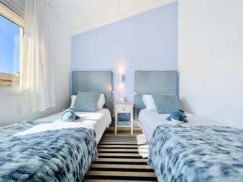 Moderno dormitorio doble en Estartit Rental en L'Estartit con cabeceros azules, ropa de cama blanca y alfombra a rayas